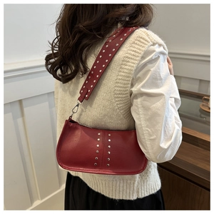 Détail du sac à bandoulière en cuir PU rouge avec clous argentés porté par un mannequin