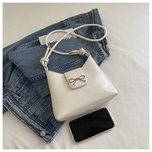 Detailed top view of white matte PU leather underarm bag with silver metal bow and knotted strap