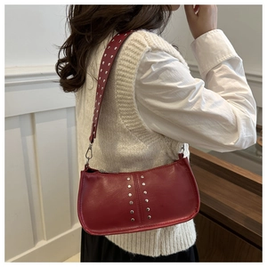 Vue détaillée du sac porté épaule en cuir bordeaux avec rivets argentés sur un modèle