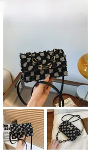 Detail view of denim crossbody bag with fringe edges and resin chain strap in black color