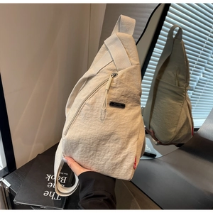 Vue détaillée du sac bandoulière en nylon beige avec texture durable et fermeture éclair