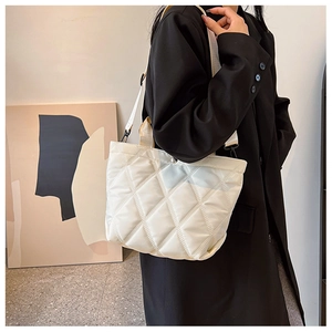 Detail view of white quilted bucket bag with adjustable strap worn by a model