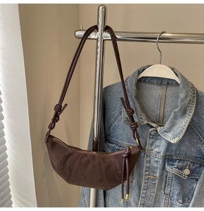Detailansicht der braunen Wildleder-Croissant-Tasche mit Nähten und goldenem Reißverschluss