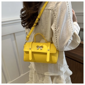 Detail of bright yellow crossbody bag with silver bow buckle and adjustable strap