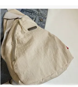 Détail du sac bandoulière en nylon blanc cassé montrant la fermeture et la texture