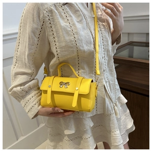 Chic yellow crossbody bag featuring a golden butterfly buckle and slim shoulder strap