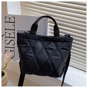 Chic black quilted bucket bag with adjustable shoulder strap near elegant tulips