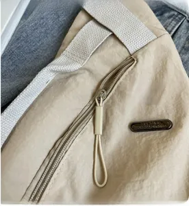 Détail de la fermeture éclair en métal et du logo Fashion sur le sac en nylon beige