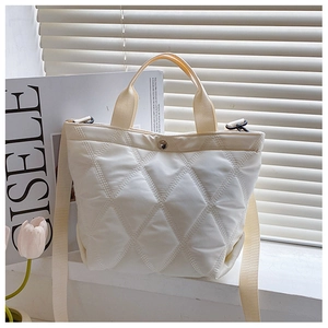 Close-up of beige quilted bucket bag with diamond stitching and silver buckle detail