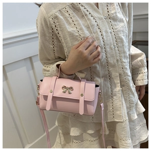 Detail of the pink mini crossbody bag featuring a golden bow and magnetic flap closure