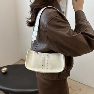 Sac baguette chic en cuir blanc avec rivets et bandoulière à œillets métalliques