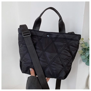 Close-up of black quilted bucket bag featuring a detachable wide fabric shoulder strap