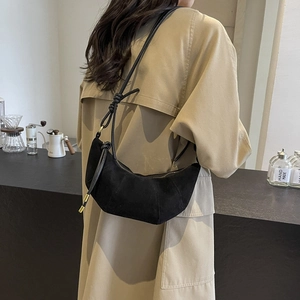Schwarze Wildleder-Halbmondtasche mit goldenem Reißverschluss, getragen zum Trenchcoat