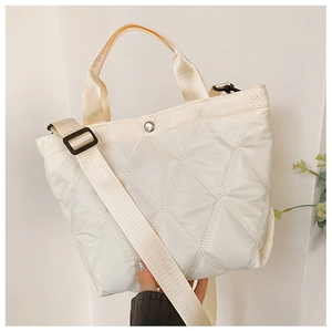Close-up of beige quilted tote bag with diamond stitching and adjustable wide strap