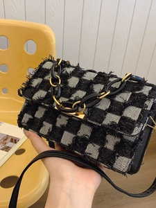 Checkerboard pattern denim crossbody bag with fringe trim and golden chain strap