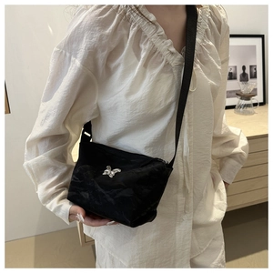 Detail van zwarte nylon crossbodytas met een sprankelende zilveren vlindergesp en diamanten
