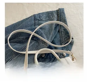Dettaglio della tracolla comfort e del gancio dorato su borsa a mano bianca minimalista