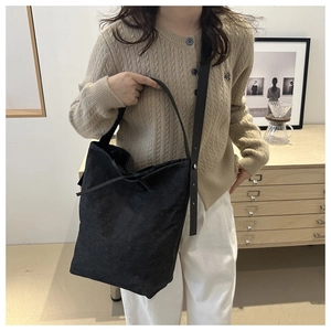 Détail du sac seau noir texturé minimaliste avec ruban décoratif et rivets argentés