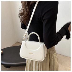 Foto lifestyle di una borsa a tracolla bianca minimalista con manico curvo e logo moda