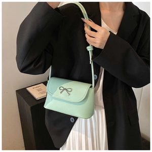Close-up of mint green leather handbag featuring a stylish silver metal bow detail