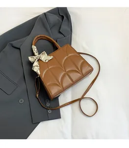 Détail du sac à main en cuir marron avec plis matelassés et foulard en soie décoratif