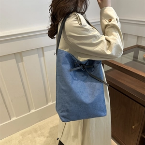 Sac seau chic en denim bleu pour femmes avec bandoulières en cuir noir et nœud