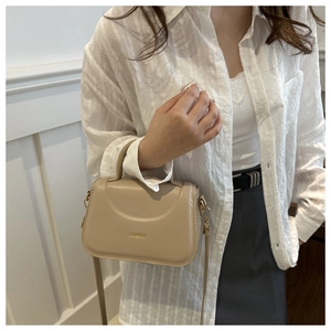 Dettaglio di una borsa a tracolla beige in pelle con scritta Fashion in metallo dorato