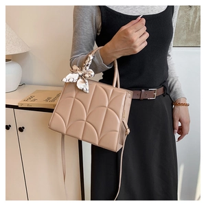 Détail du sac bandoulière abricot avec matelassage courbé et élégant foulard en soie
