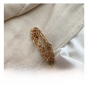 Detail of high-gloss gold alloy chain strap on minimalist shoulder bag with textile background