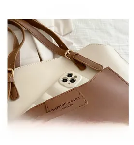 Dettaglio della borsa tote in pelle bicolore con tasca frontale e logo inciso di alta qualità