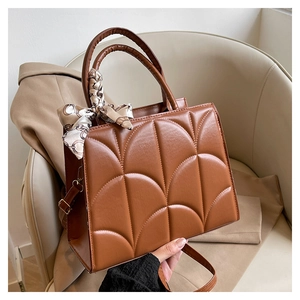 Détail du sac à main marron caramel en similicuir avec foulard et motif matelassé