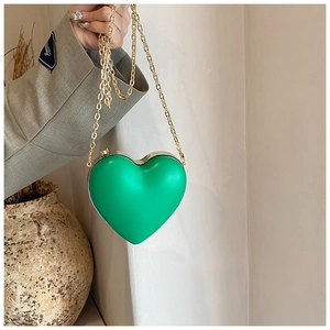 Detail of bright green heart-shaped hard shell clutch bag with gold chain strap