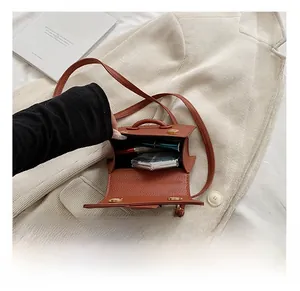 Rangement interne du sac à main marron à motif litchi montrant des cosmétiques