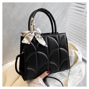 Détail du sac à main matelassé noir avec foulard en soie décoratif sur la poignée