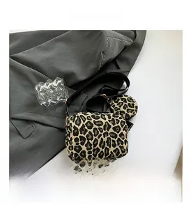 Gros plan sur un sac bandoulière léopard avec sa mini pochette ronde assortie sur un veston
