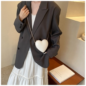 Detail shot of the white heart-shaped mini bag with elegant gold metal chain strap