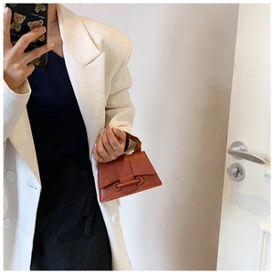 Détail du sac à main en cuir à motif litchi avec boucle ronde unique en finition marron