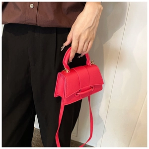 Détails de la texture grain litchi sur le sac à main rouge en cuir synthétique avec boucle