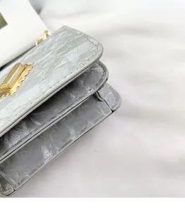 Detail view of silver square bag showing side accordion folds and precision stitching