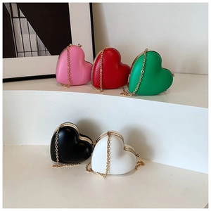 Macro detail of various colorful heart-shaped chain bags with gold metal frames and straps