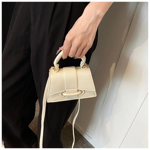 Vue détaillée du cuir beige à grain de litchi sur la base incurvée de ce sac à main chic