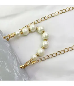 Detail of elegant gold metal chain featuring white pearls and sparkling crystal rings