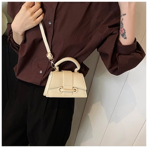 Vue détaillée du mini sac à main crème avec grain de litchi porté par un mannequin