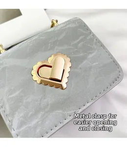 Detail of golden heart-shaped metal lock on marble texture crossbody bag with pearl handle