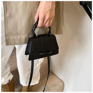 Gros plan du sac à main noir en cuir grainé avec une base incurvée en forme de sablier