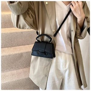 Détail du mini sac à main noir en cuir grainé avec finitions dorées et bandoulière fine