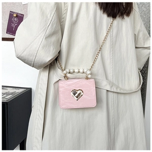 Detail of pink mini bag with ruched leather, gold heart buckle, and pearl top handle