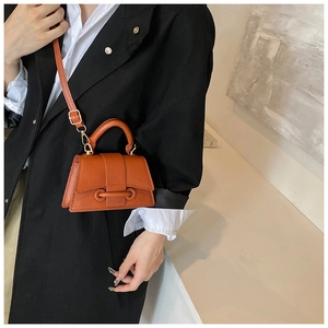 Détail du mini sac orange en cuir grainé avec base incurvée et éléments métalliques dorés