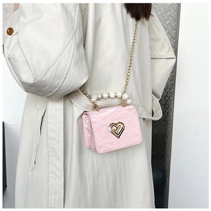 Pink mini crossbody bag featuring a golden heart clasp and elegant pearl handle