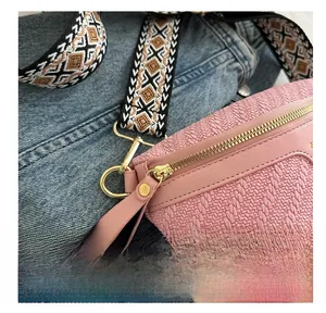 Dettaglio della borsa a tracolla rosa intrecciata con zip dorata e tracolla geometrica